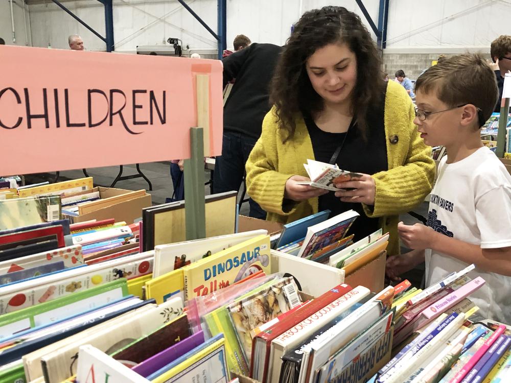 A mother and son browse books in the children's section of the AAUW book sale.