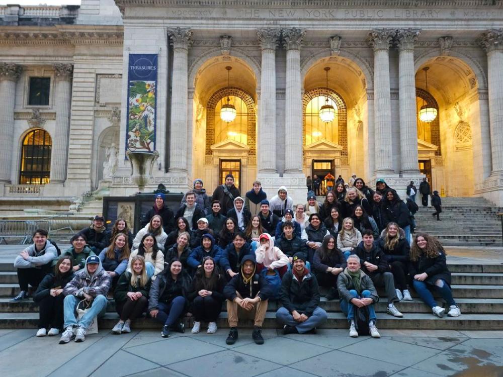 A group of people posing for a photograph on the steps of the New York City Public Library. 