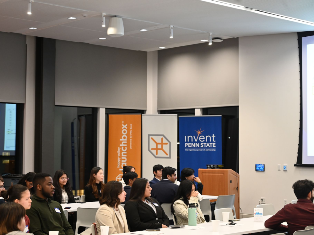 Students sitting at rows of tables during pitch competition