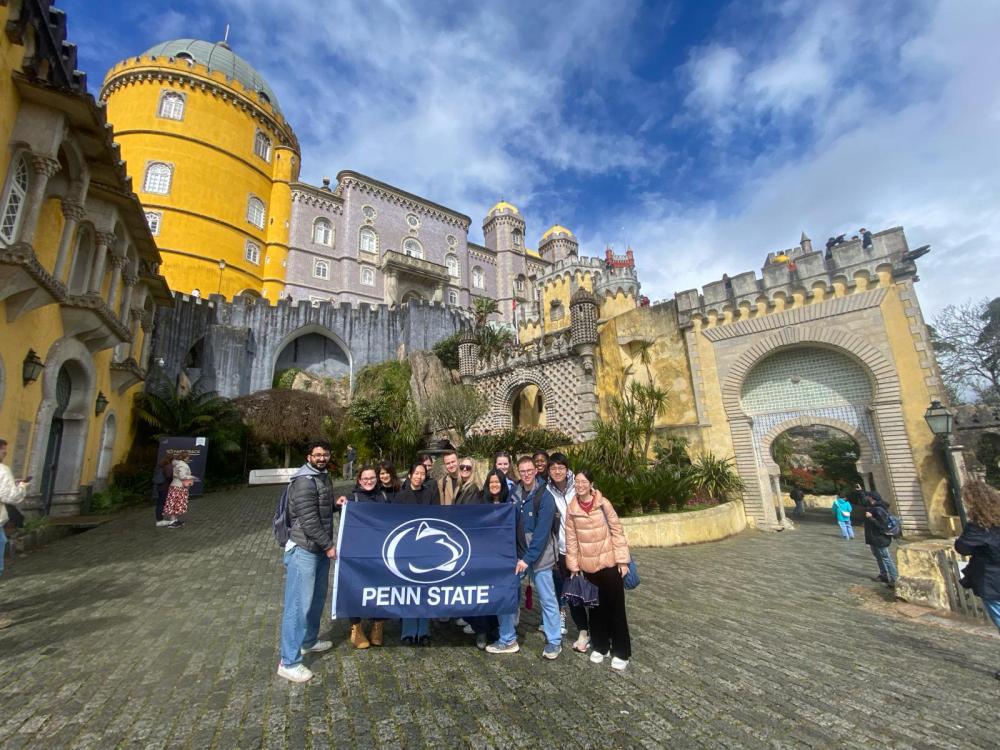 GLIS 400Y students hold a Penn State flag at Pena Palace in Sintra, Portugal. 