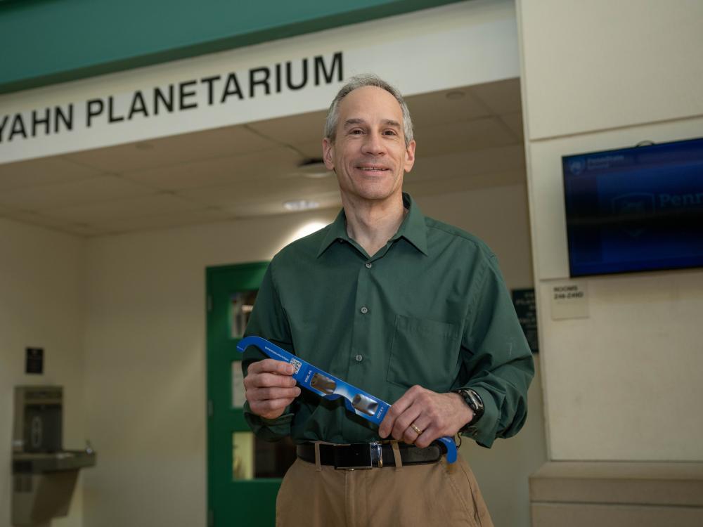 Jim Gavio, director of Penn State Behrend's Yahn Planetarium, holds eclipse glasses.