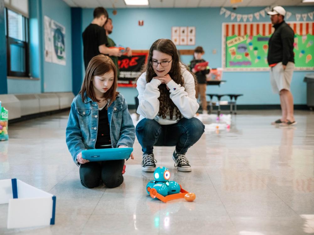 College student helps elementary school student with robot