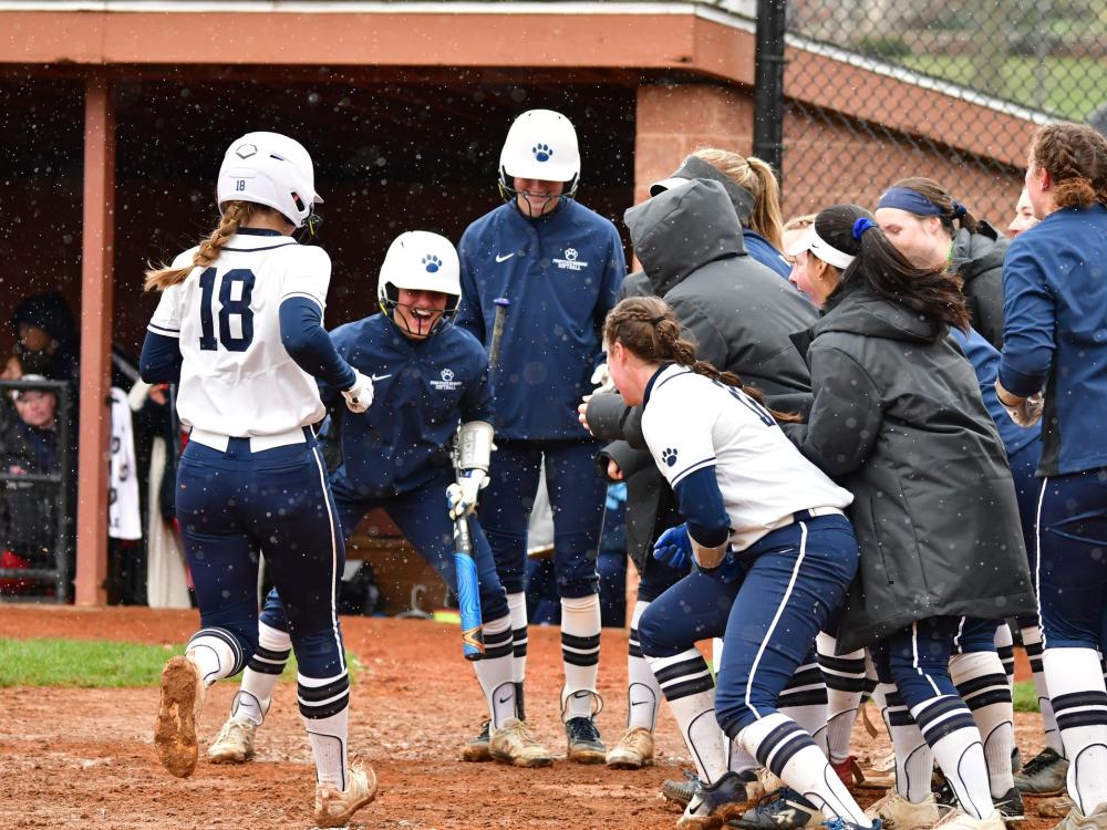 Members of the Penn State Behrend softball team cheer after a teammate scores a run.