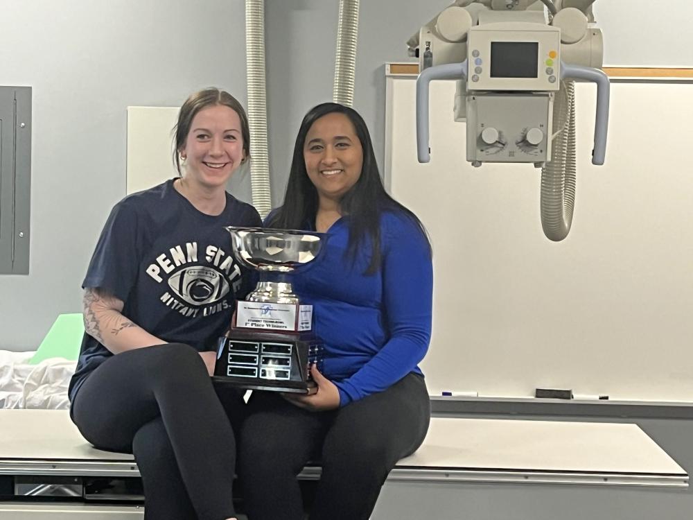 Two students hold trophy while smiling