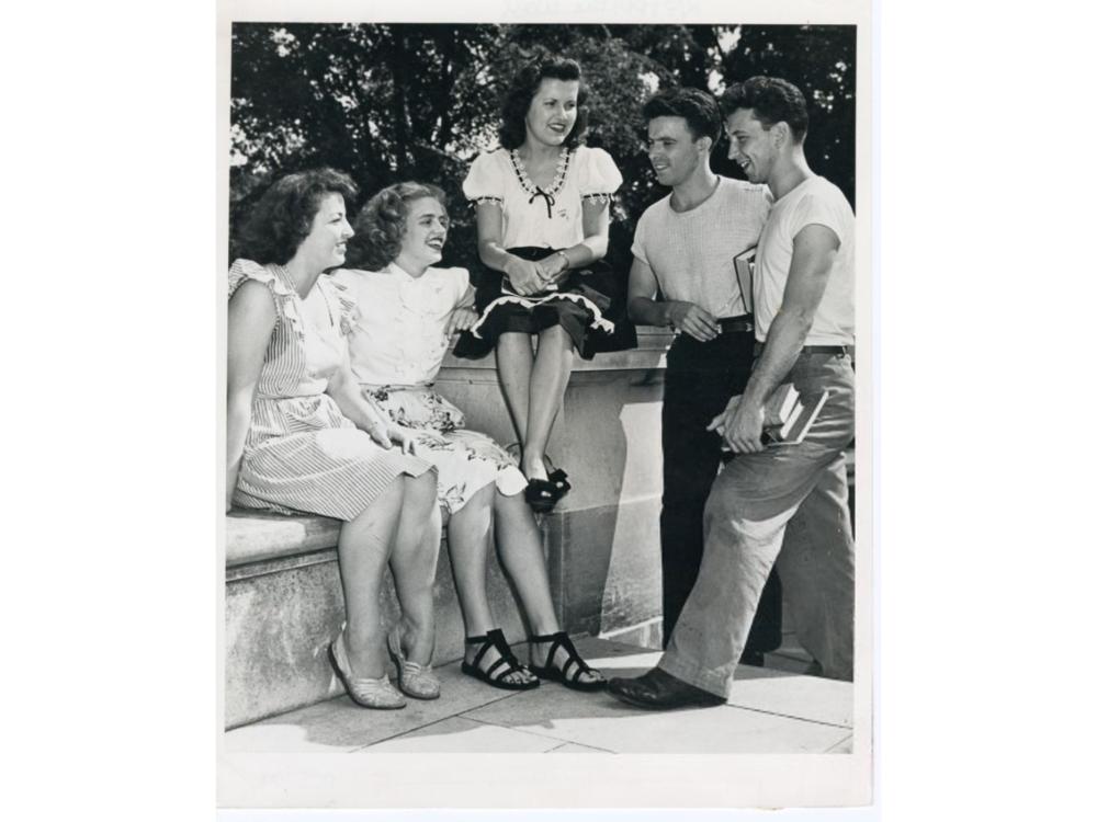 A group of students sitting on a stone wall