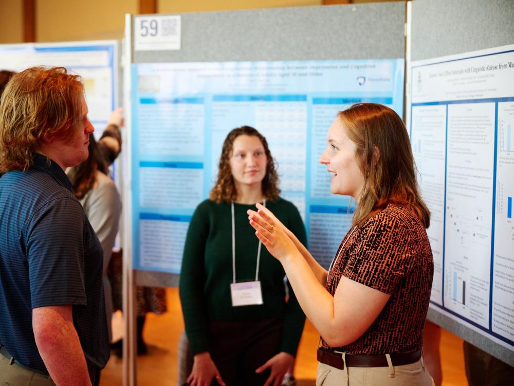 Student exhibition presenter talking in front of research poster