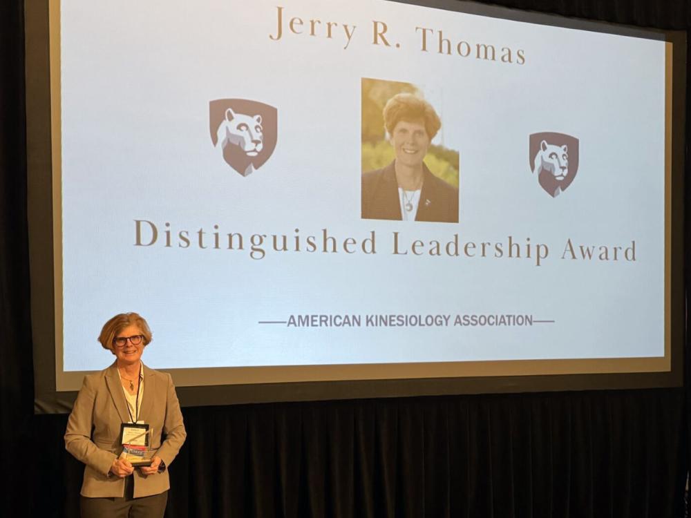 Nancy Williams holding award in front of screen reading Jerry R. Thomas Distinguished Leadership Award