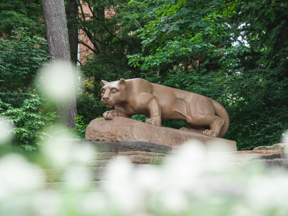 The Penn State Nittany Lion Shrine is shown in focus behind spring flowers in 2019.