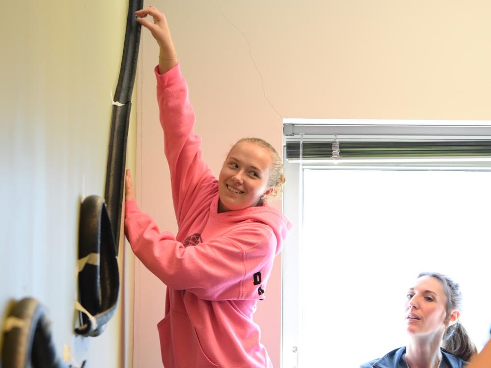 A middle-school student reaches up to place a marble in a model roller coaster track.