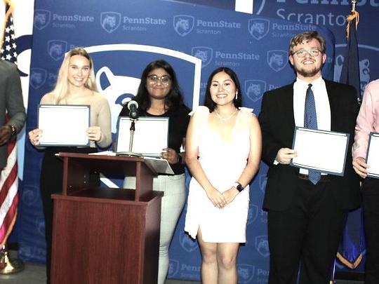 a group of students show off their award certificates onstage at the annual dinner event