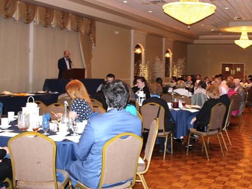 Chanceller wafa stands at podium and addresses the seated crowd at annual awards dinner