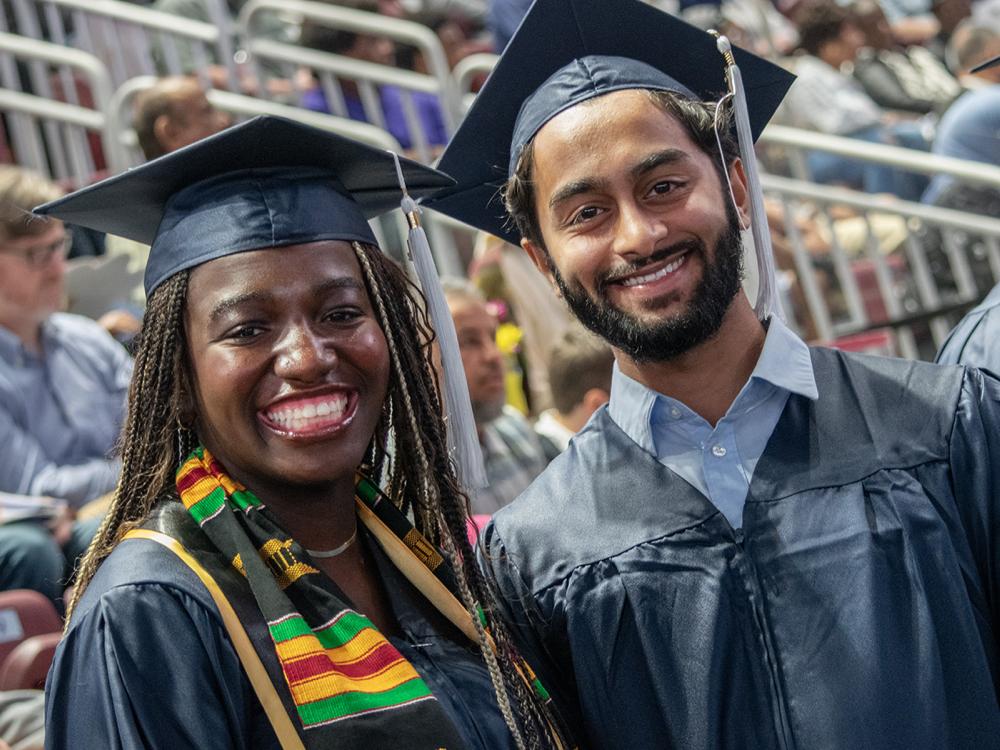 two students posing in caps and gowns at commencement