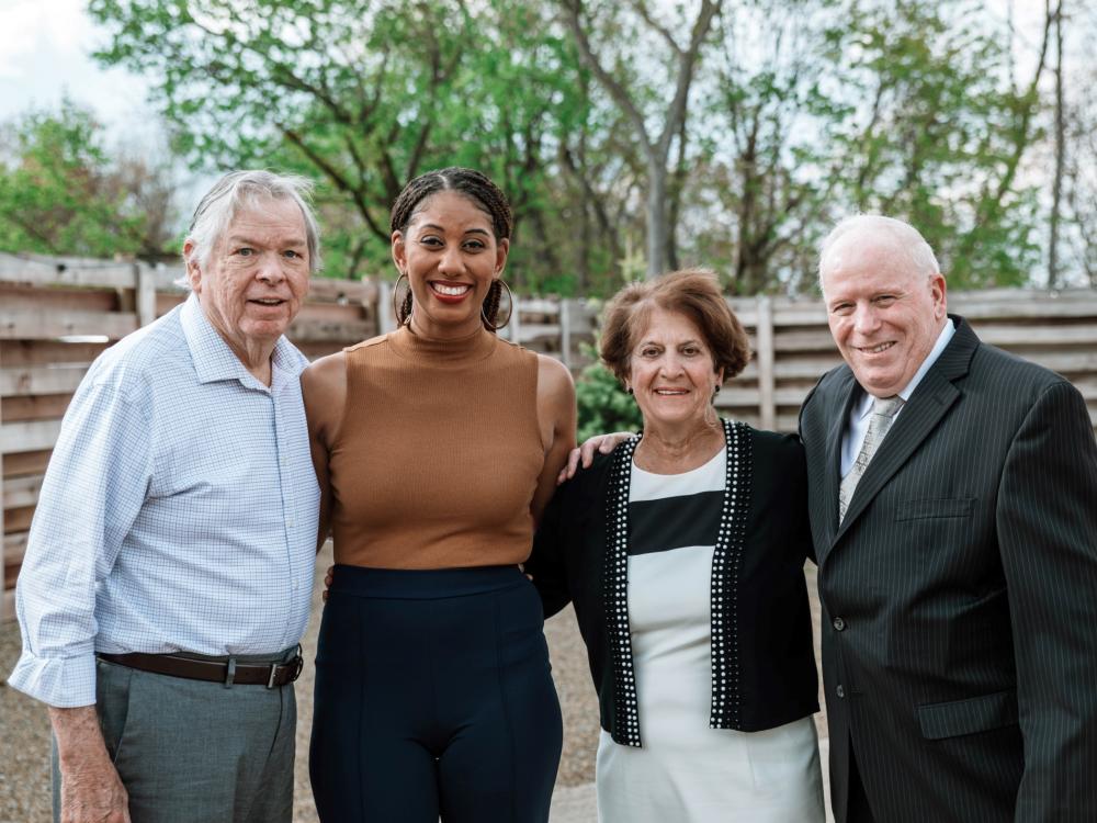 Four individuals stand smiling and posing for photo