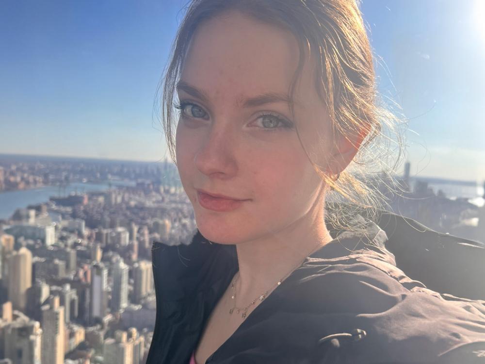 A selfie of Johnna D’Ecclesiis with a high-rise view of a city in the background.