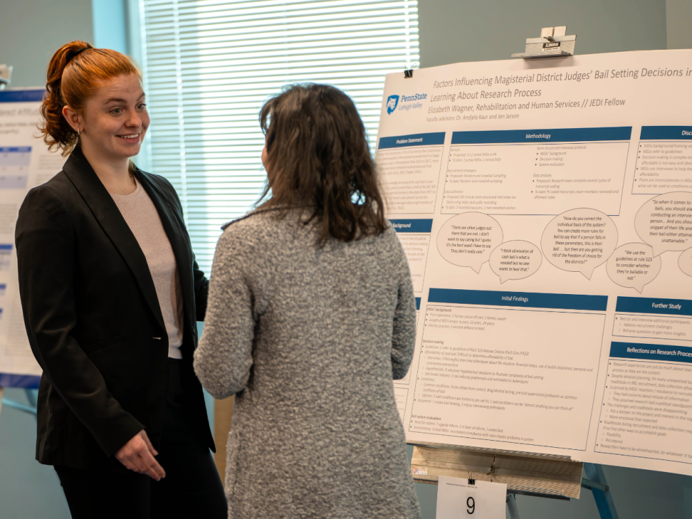 Two people talk in front of a research poster
