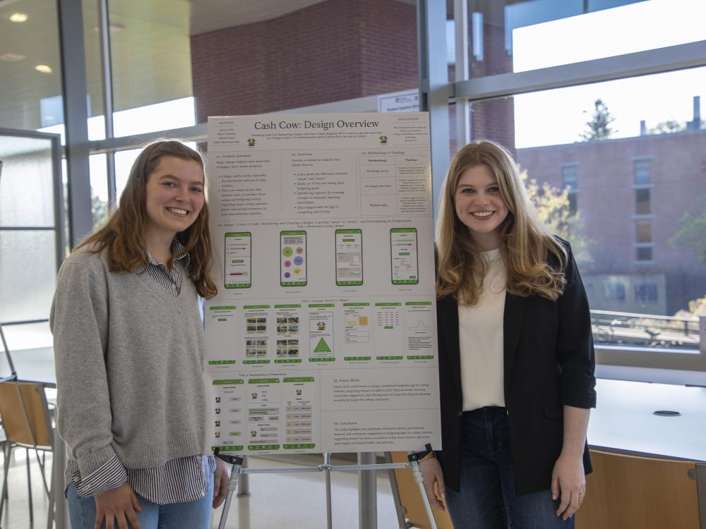 two smiling people with long hair in college campus building