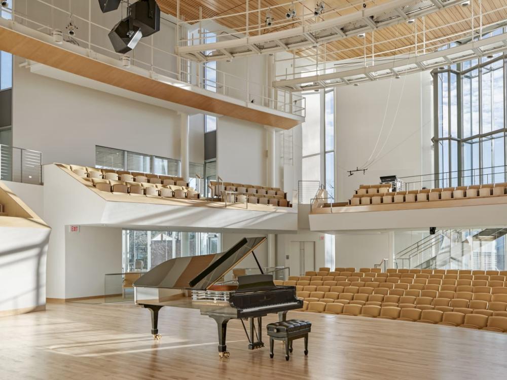Interior of a recital hall with a grand piano at center stage.
