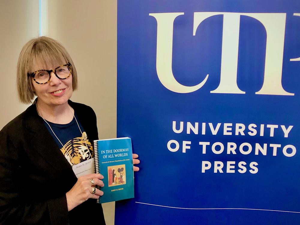 Robin Bower stands with her book in front of a UTP sign