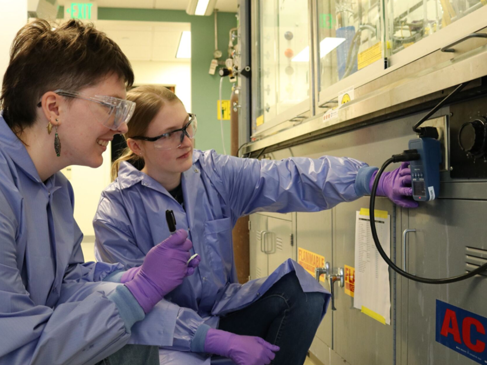 Two students in lab coats and goggles