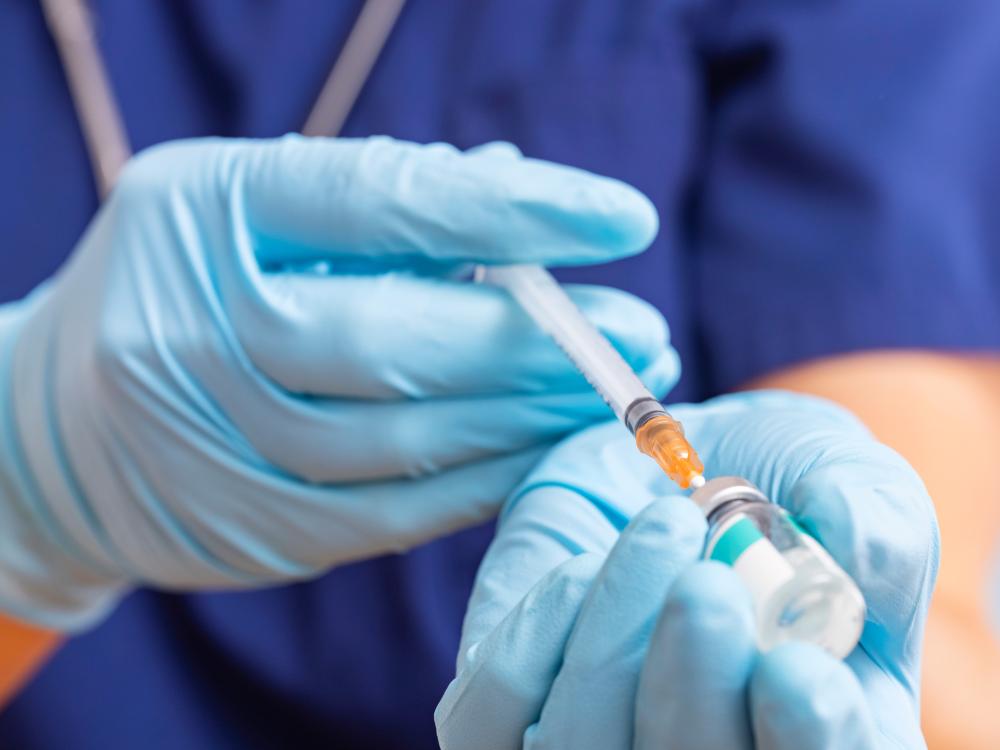 Close-up image of health care professional filling syringe with medicine from a vial