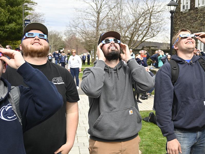 People wearing special glasses while looking at the sky.