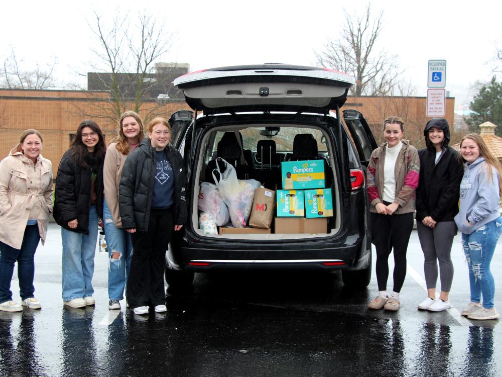 Members of the HDFS club at Penn State DuBois stand next to the vehicle loaded with their donation items prior to their trip to the Hello Neighbor location in Pittsburgh.