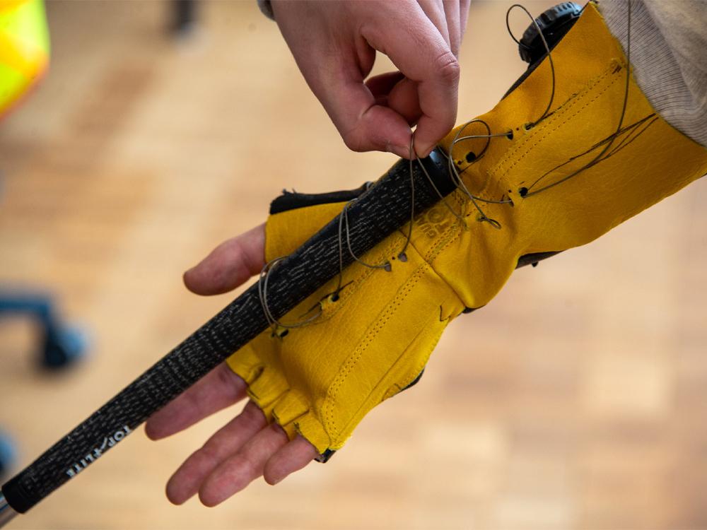 A golf club attaches to a yellow glove via a thin wire that holds it in place.