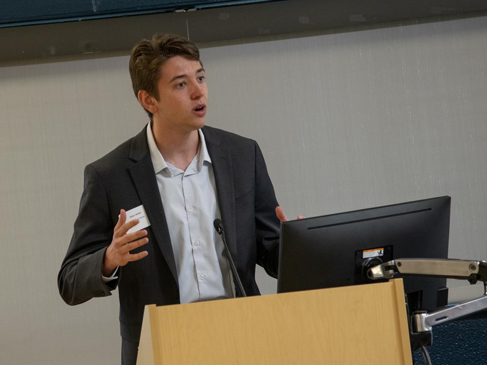 Aiden Beiler stands at a lectern while making a business pitch