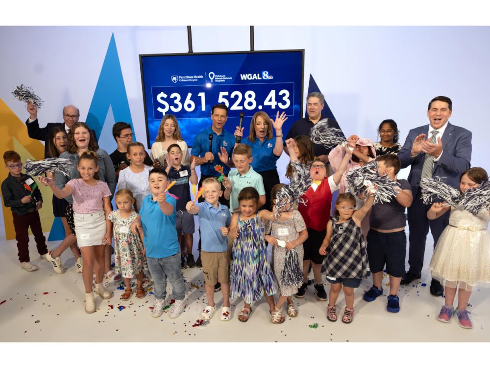 Several people stand in front of an electronic display with the amount $361,528.43 on it.