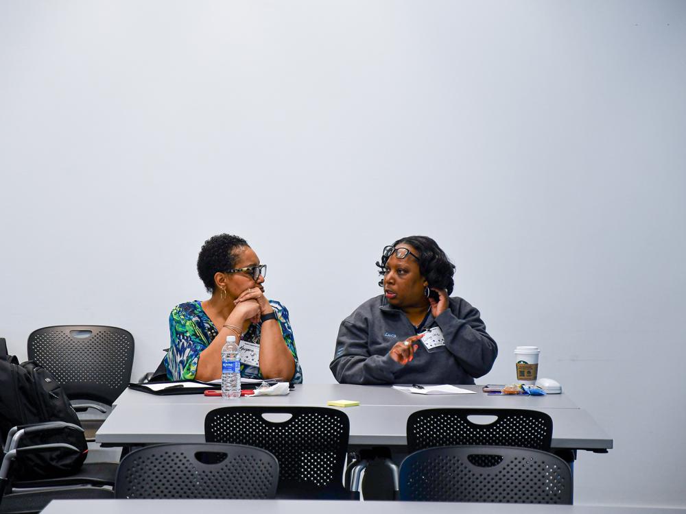 Two women sit at a table talking