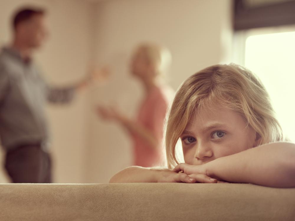 Image of a child with parents arguing in the background