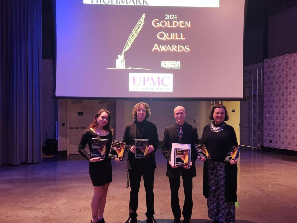 Four smiling people holding award plaques