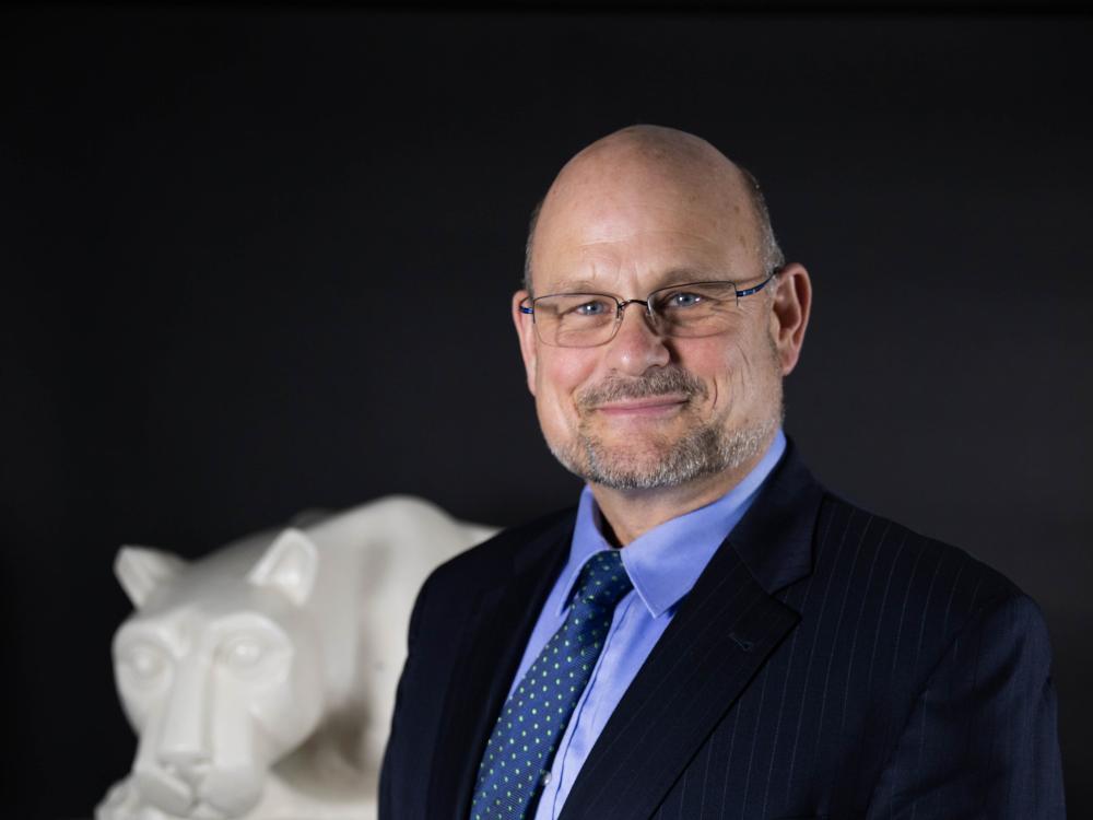 Kevin Snider, chancellor, stands in front of lion shrine statue