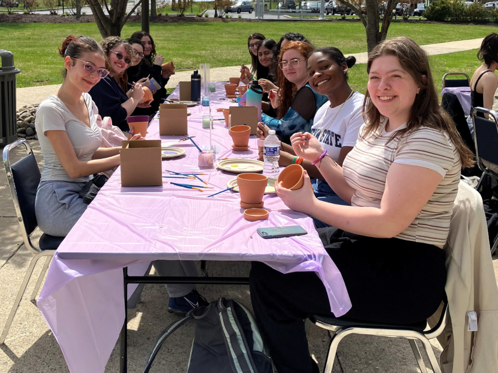 students paint flower pots outdoors 