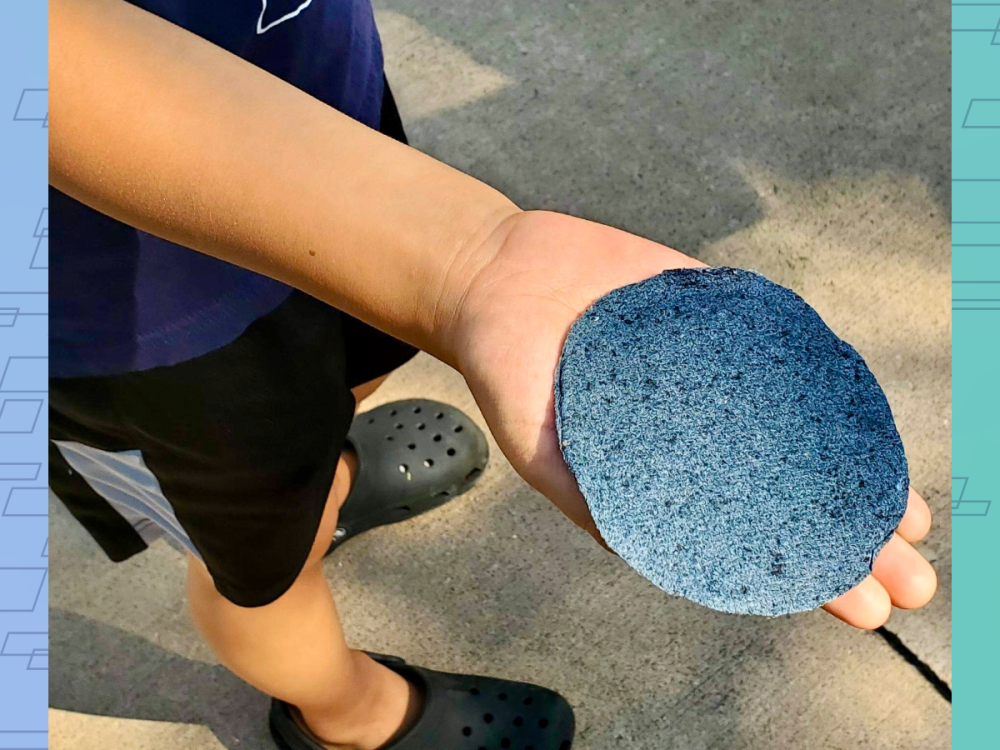 closeup of child's hand holding palm sized disk of blue flecked paper