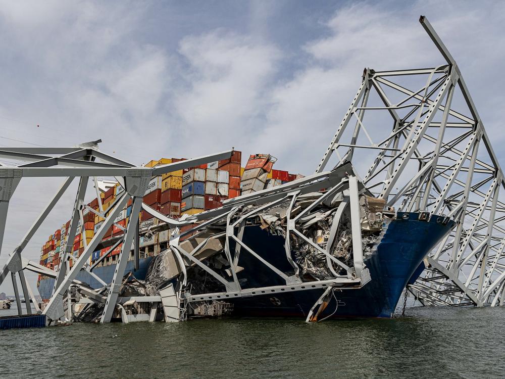 Cargo ship under bridge wreckage