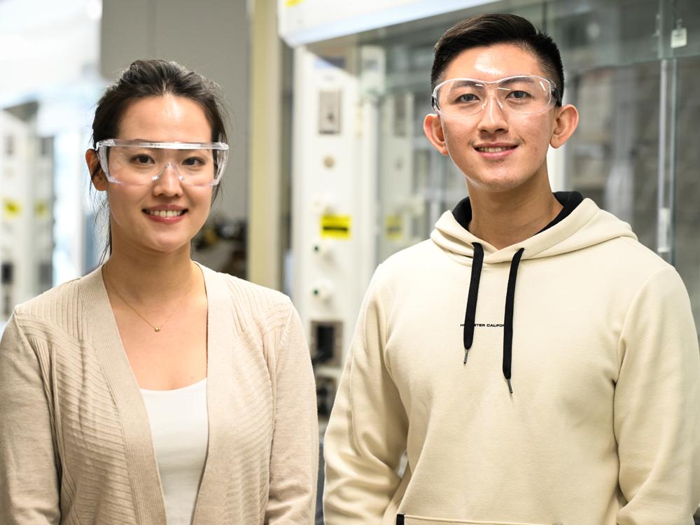 Two individuals wearing safety glasses pose in a lab.