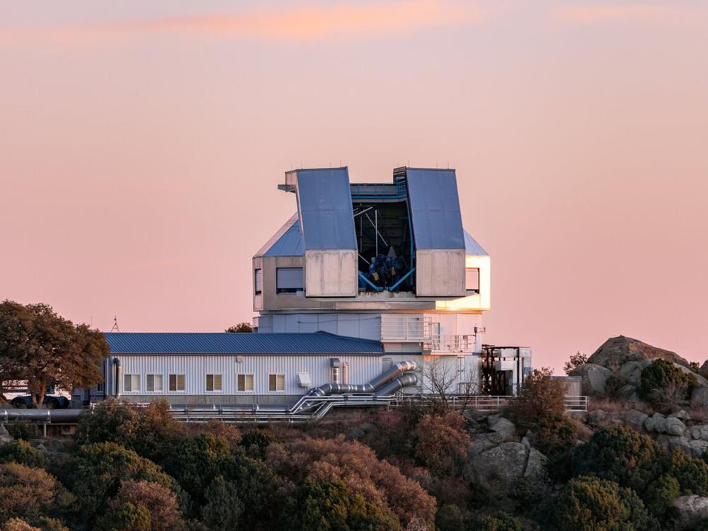 A large metallic building with a telescope on the roof