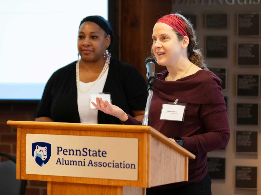 woman speaking at podium with colleague looking on