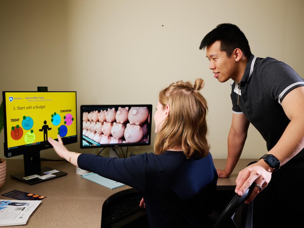 Two people at a computer screen watching online webinar