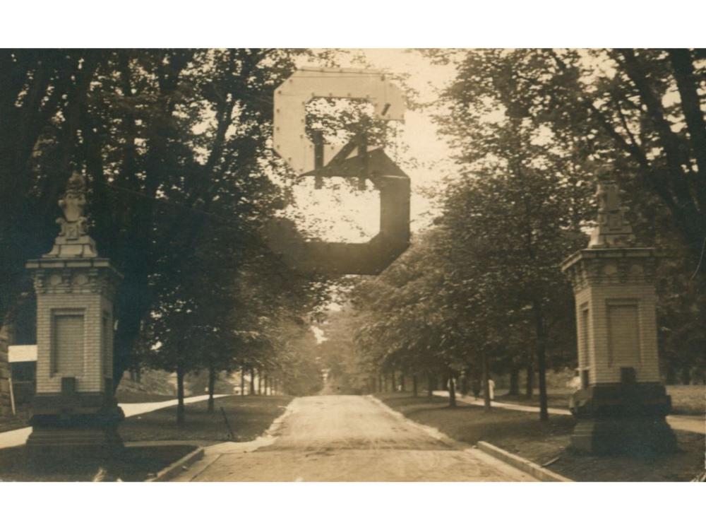 An “S” ornament hangs above the main entrance at Allen Street for commencement ceremonies in 1914. The statues of “Ma” and “Pa” lions can be seen at the top of each pillar.