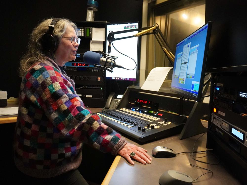 WPSU host in colorful sweater reads copy on air