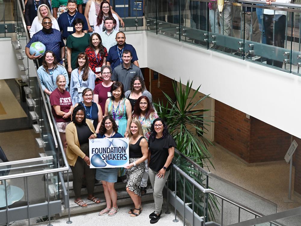 The first cohort of World Campus D.Ed. students pose on the stairs in the atrium of Chambers Building.