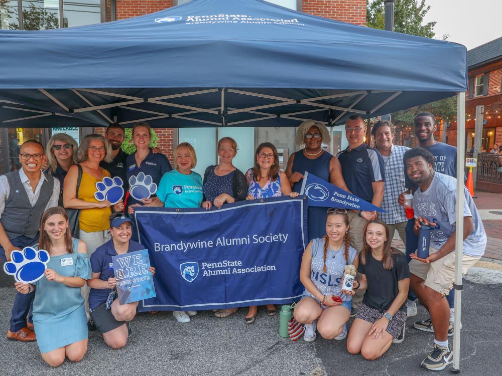 group of people at Dining Under the Stars holding Brandywine Alumni Society banner