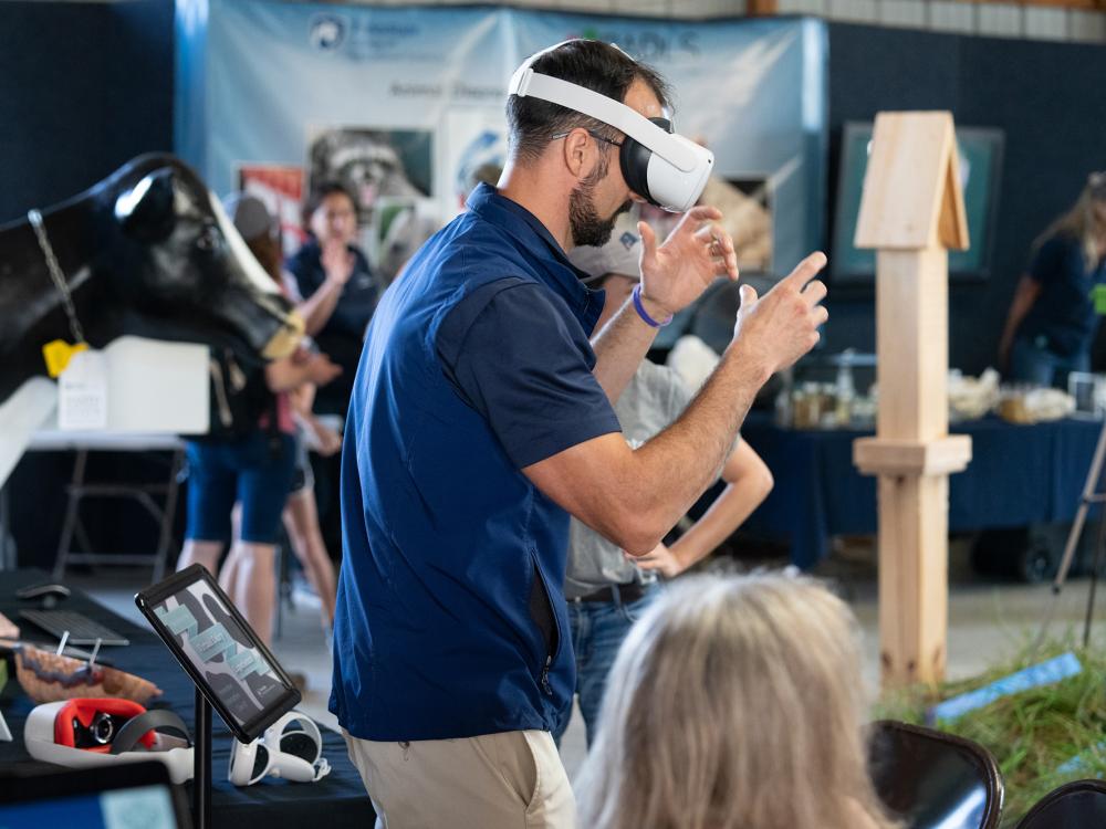 A man stands with a virtual reality headset on, facing to the side.