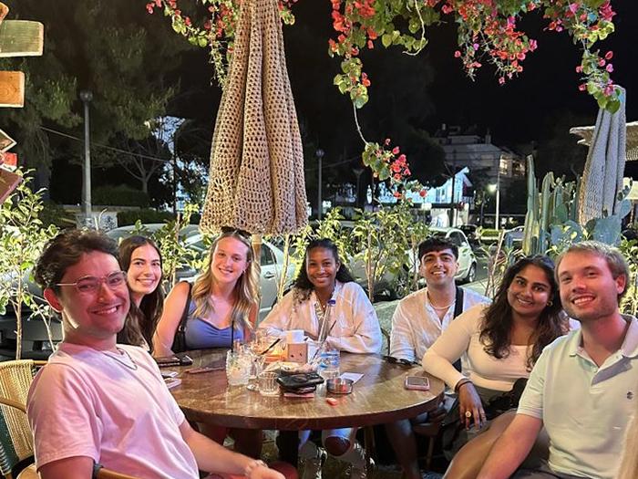 Seven Penn State students sit around a table at a restaurant in Greece.