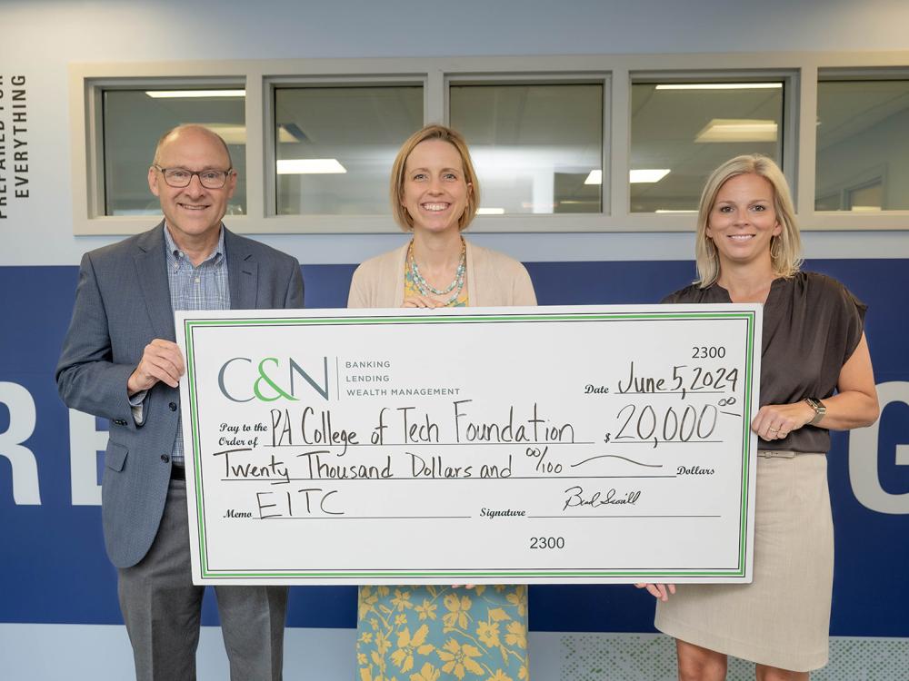 Three people hold up a giant check