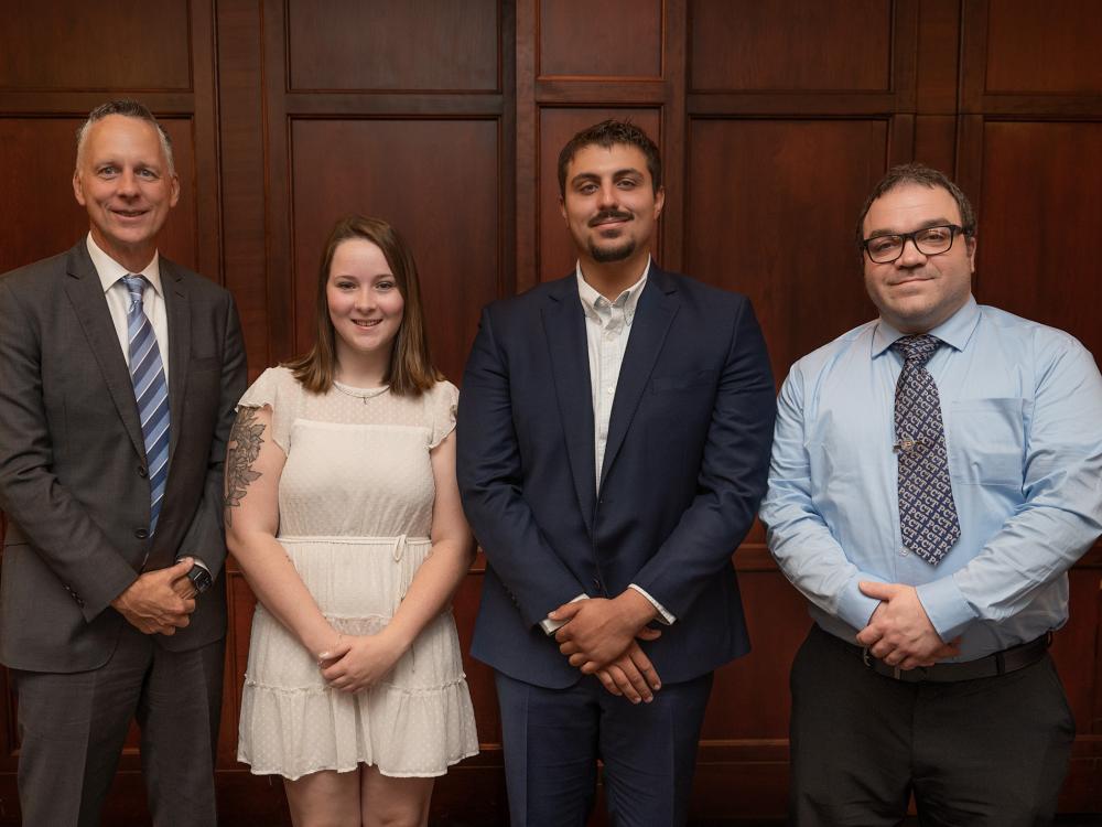 Four people dressed in business casual pose for a photo.