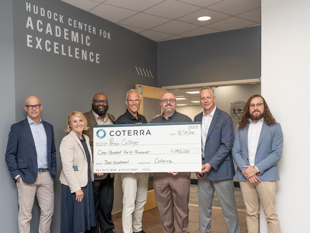 A group of people hold up a very large check for a photograph