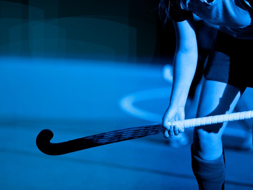 Blue-tinted graphic/photo of a field hockey player holding a field hockey stick